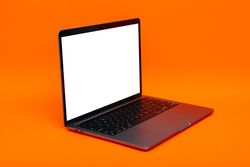 Laptop at angle with mockup screen in orange studio