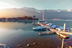 Tranquil lake with boats on pier against mountains