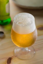 Freshly poured pint of beer overflowing with foam