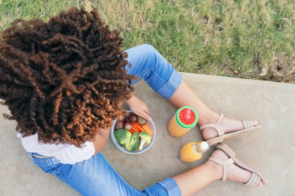 Girl eating vegetables during the day.