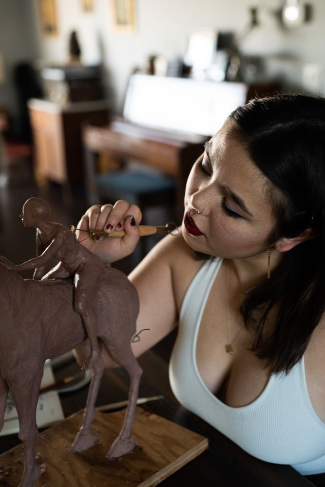 Close up of young woman working on small sculpture inside house