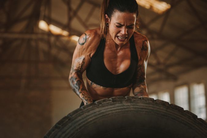 Strong woman performing tire flipping workout