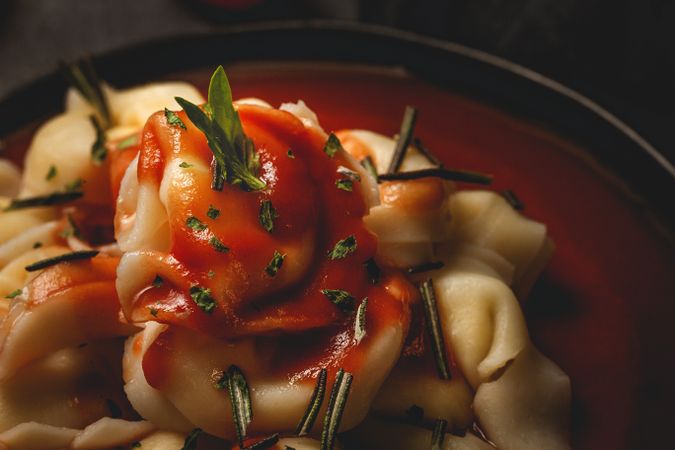 Plate of delicious ravioli with tomato sauce served on table