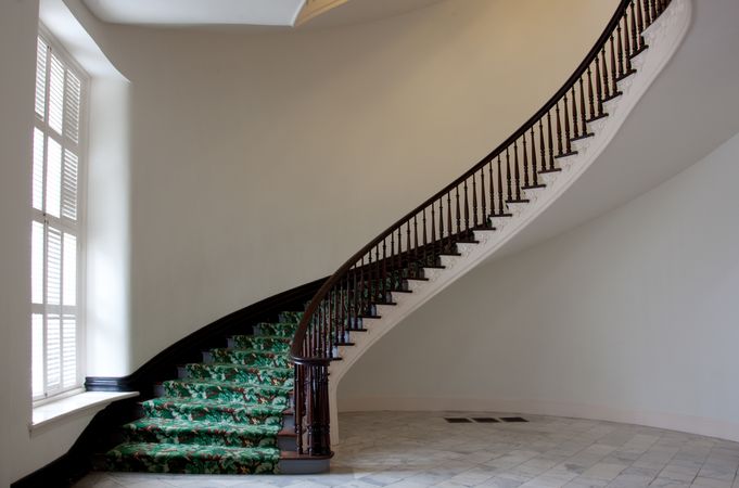 Elegant curved staircase with green carpet in Montgomery Capitol building