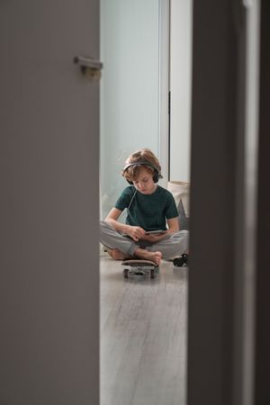 Boy sitting on skateboard with tablet