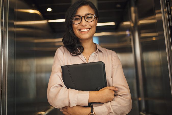 Smiling business woman in office elevator