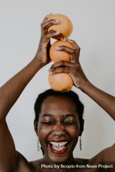 Woman holding orange fruit over her head smiling 0WJeOb