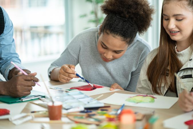 Girl drawing and painting with friends in arts class