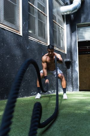 Strong Hispanic woman exercising with battle ropes
