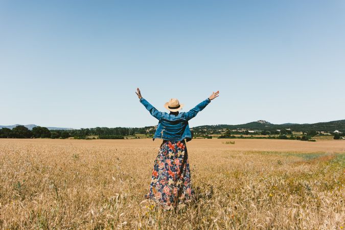 Female farmer with hat looking at her wheat crop.