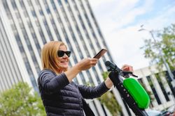 Woman browsing smartphone and riding electric scooter