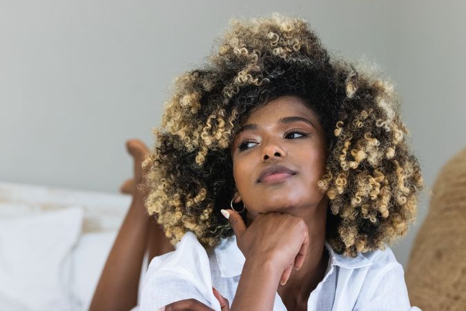 Thoughtful Black woman lying on bed in bedroom