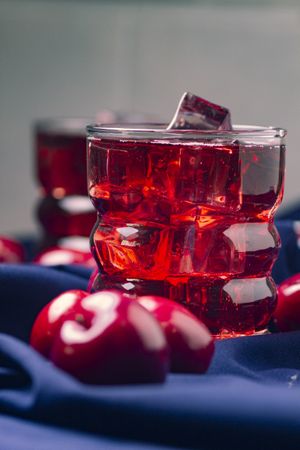 Red beverage near fresh fruits on cloth