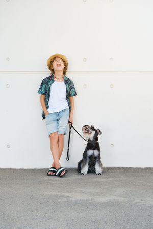 Stylish boy screaming with dog on sidewalk