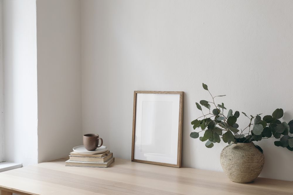 Mock up poster on table with vase, eucalyptus leaves, books and coffee