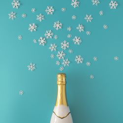 Bottle of sparkling wine on blue background with snowflakes