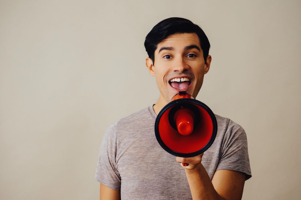 Hispanic male speaking through red loudspeaker