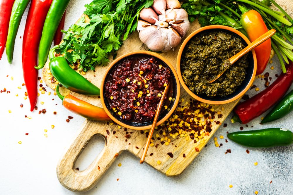 Looking down at pot of traditional Georgian sauce Adjika with garlic bulb & raw ingredient with space for text