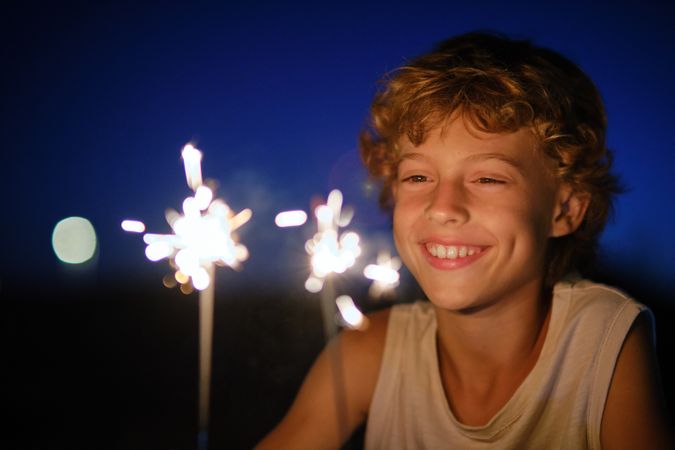 Delighted boy with Bengal lights at night