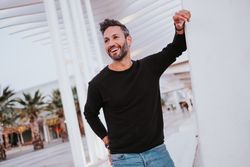 Adult stylish smiling man near grey wall on street