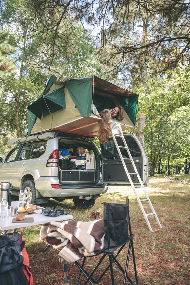 Women resting and talking lying in tent over car