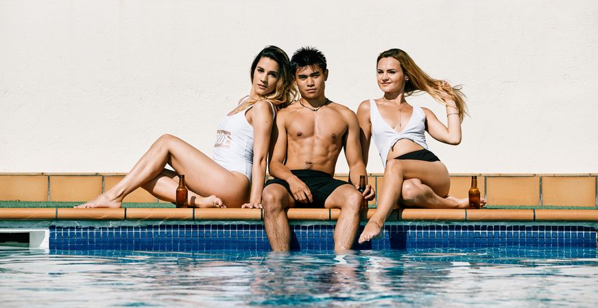 a group of young models by the pool in a summer day