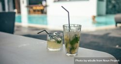 Two cocktails on a table with pool view behind 4OyBE0