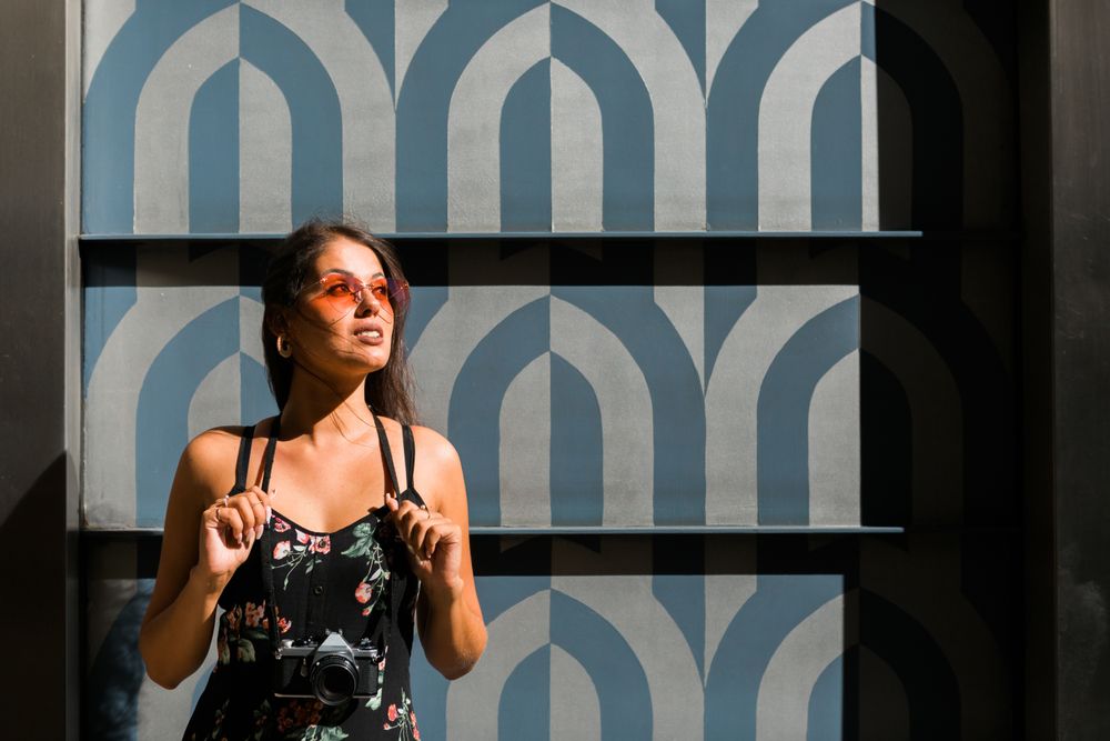 Dreamy stylish woman in sunglasses standing on city street