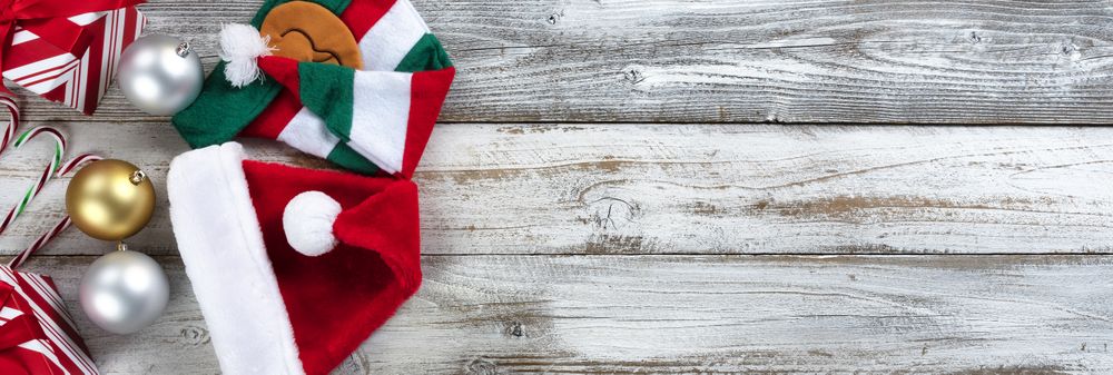Traditional silver and gold Christmas balls with presents, Santa, elf cap, candy canes and pine cones on wood