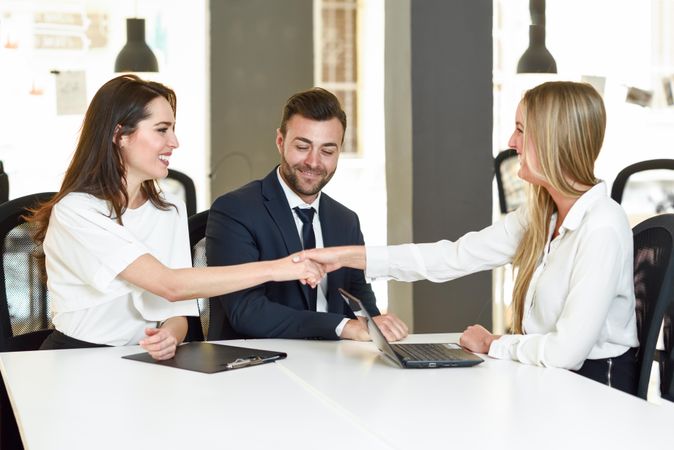 Two women shaking hands after meeting in stylish office