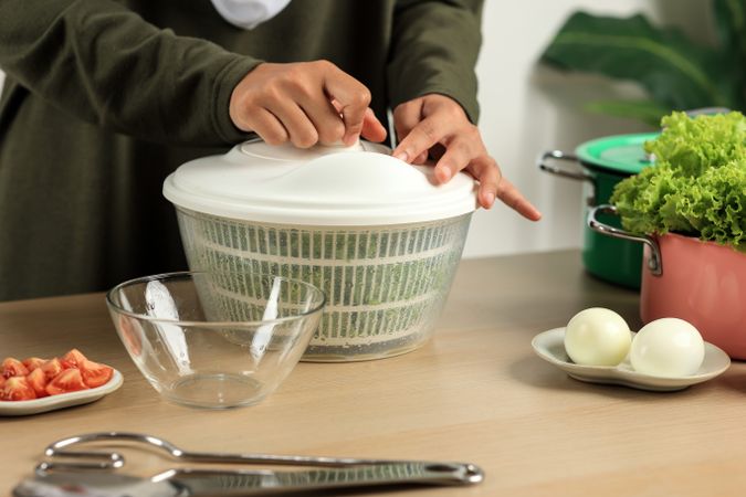 Woman Drains Lettuce from the Water in a Salad Spinner