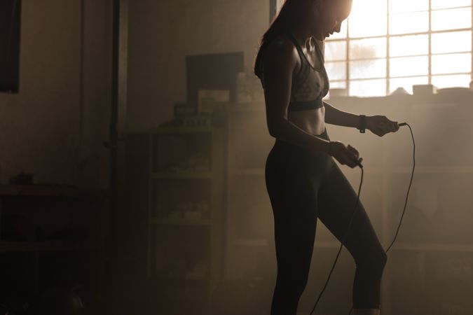 Female exercising with skipping rope at gym