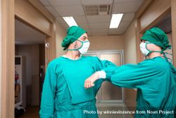 Two medical professionals greeting each other with a safe socially distanced elbow bump 4dQPnb