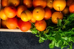 Top view of wooden box of plums with parsley