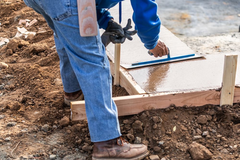 Construction Worker Using Trowel On Wet Cement Forming Coping Around New Pool