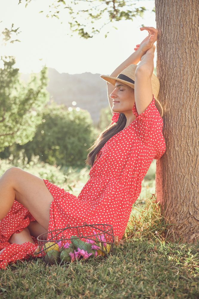 Smiling woman in red dress sitting on grass