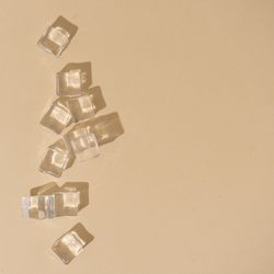 Flat lay of ice cubes on beige background with shadows