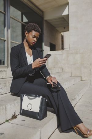 Stylish black woman with handbag and sunglasses on steps