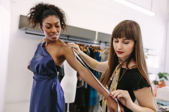 Young fashion designer taking measurements of model to design new clothes