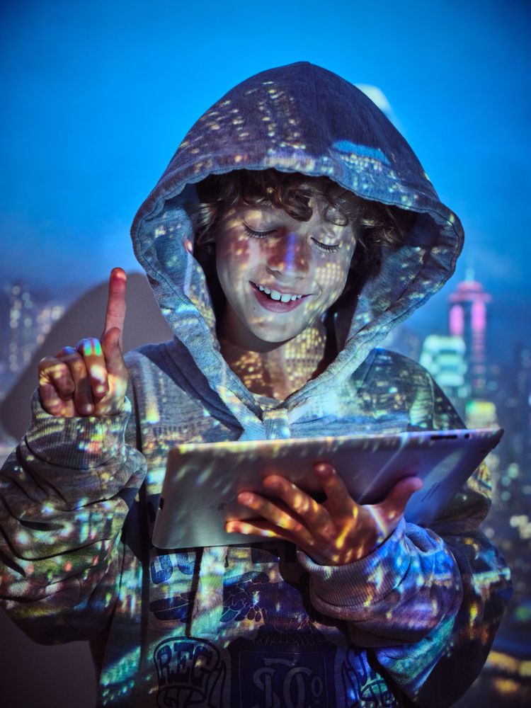 Cheerful boy with tablet through bright light