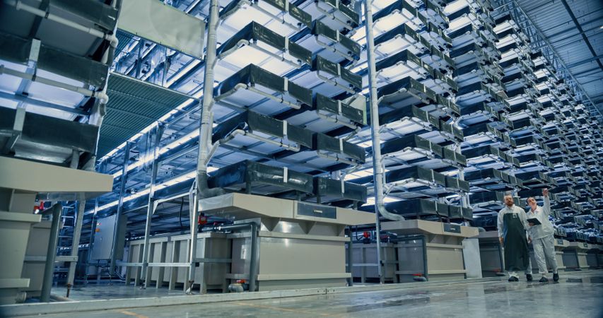 Vertical Farm Operators Having a Conversation at Work while Walking in a Hall with Plants on a Rack.