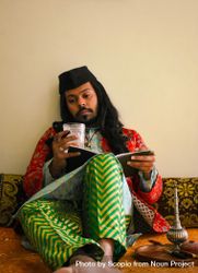 Indian man with long hair sitting and writing on a notebook 0KRO1b