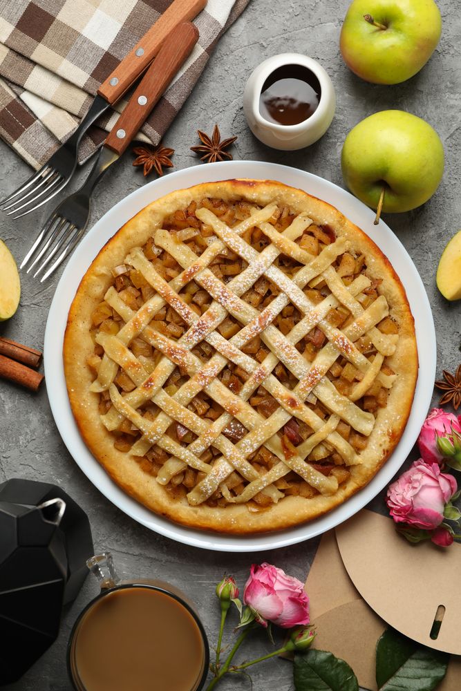 Composition with apple pie and ingredients on gray background, top view