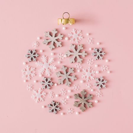 Snowflakes making shape of holiday decoration on pink background