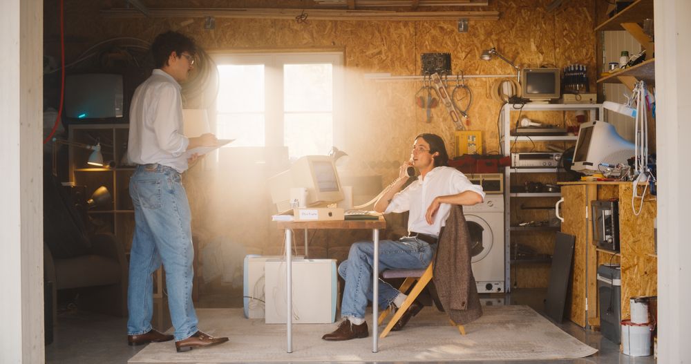 Stock Traders Working In Retro Garage, Using Old Desktop Computer With Candlestick Chart And Landline Phone To Pitch A Public Company To Investors.