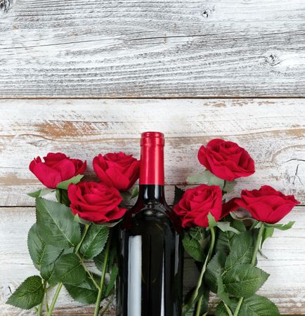 Valentine’s Day celebration with red wine and roses on bottom of rustic wooden boards