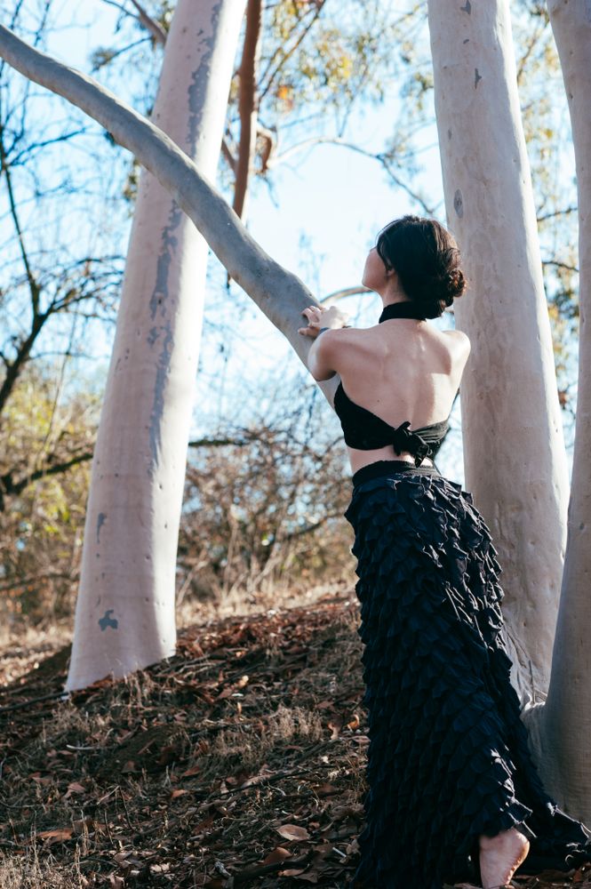 Woman standing near a tree with formal shirt and skirt