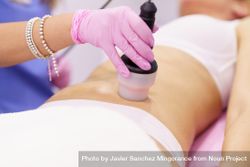 Professional in scrubs performing cosmetic procedure on stomach 5l31Y0