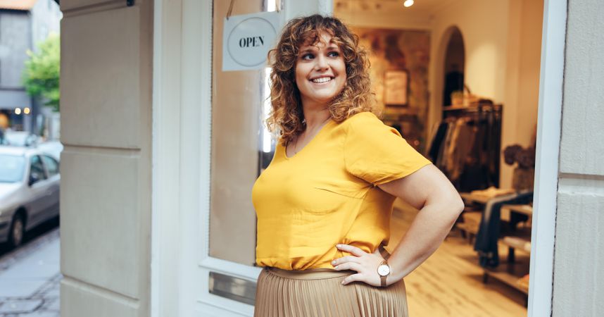 Fashion boutique owner standing outside her shop with her hands on hips