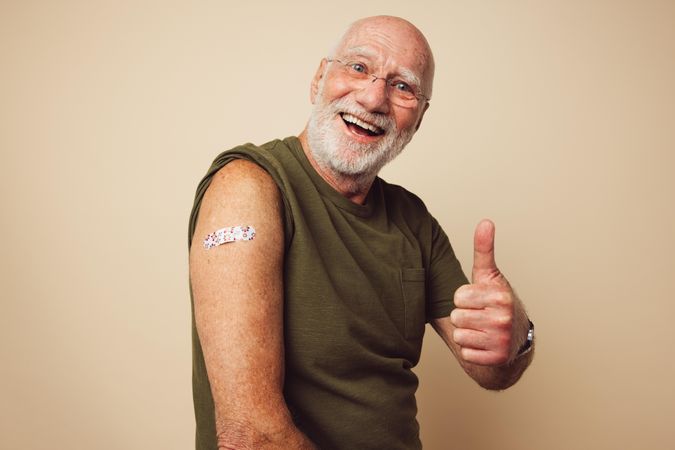 Portrait of a older male smiling and showing thumbs up after getting a vaccine